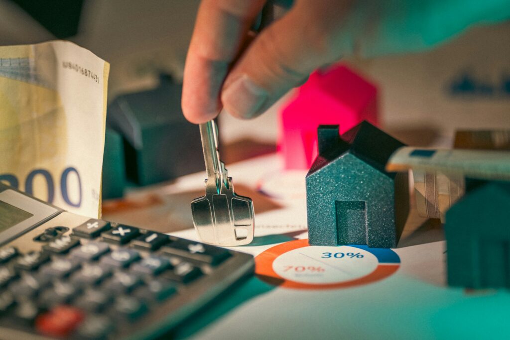 Close-up of keys, miniature house models, and financial documents, representing tips for maximizing income potential through Airbnb property management.