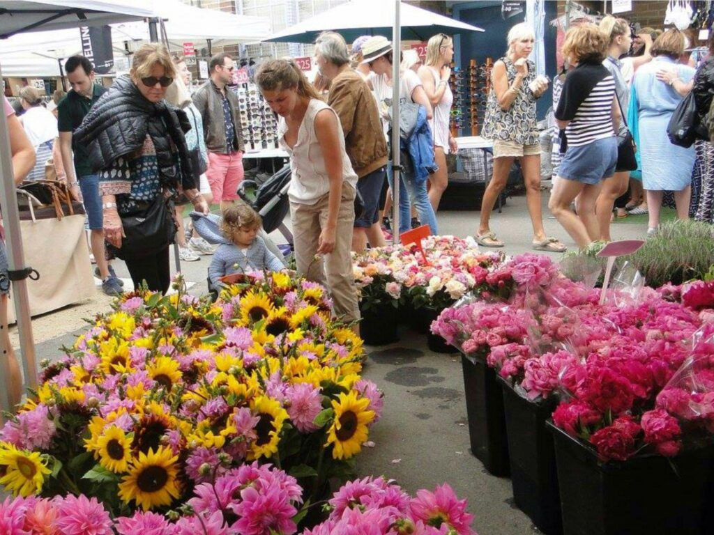 Visitors browse vibrant flower stalls at Bondi Markets, a popular Sunday event near Bondi Beach featuring local crafts, vintage clothing, and delicious food.