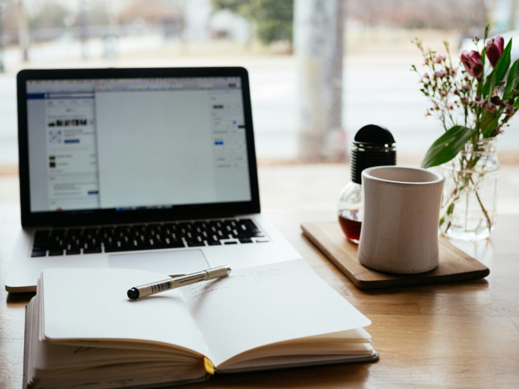 Cozy workspace setup with a laptop, notebook, and coffee, illustrating Airbnb's appeal for remote work compared to traditional hotel stays.